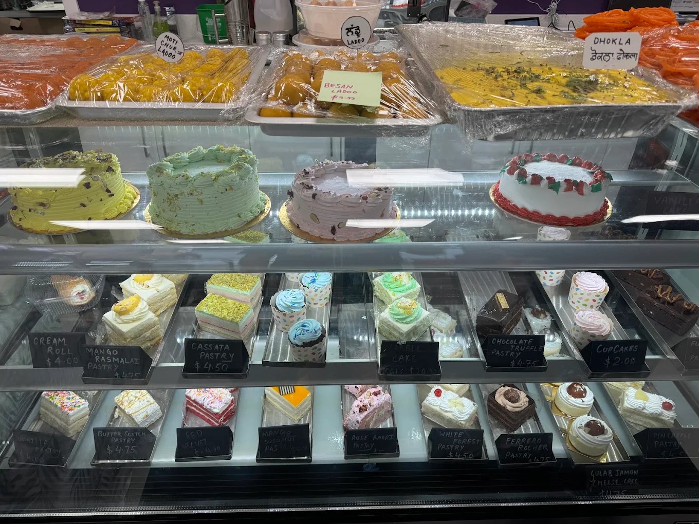 Display case of Indian sweets, cakes and pastries with labels