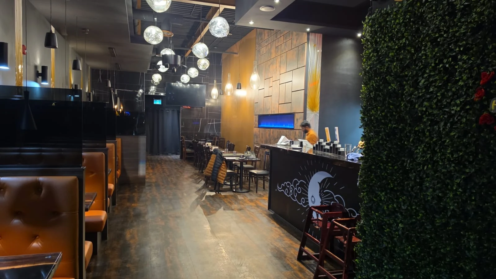 Restaurant dining room with tables, warm lights and greenery