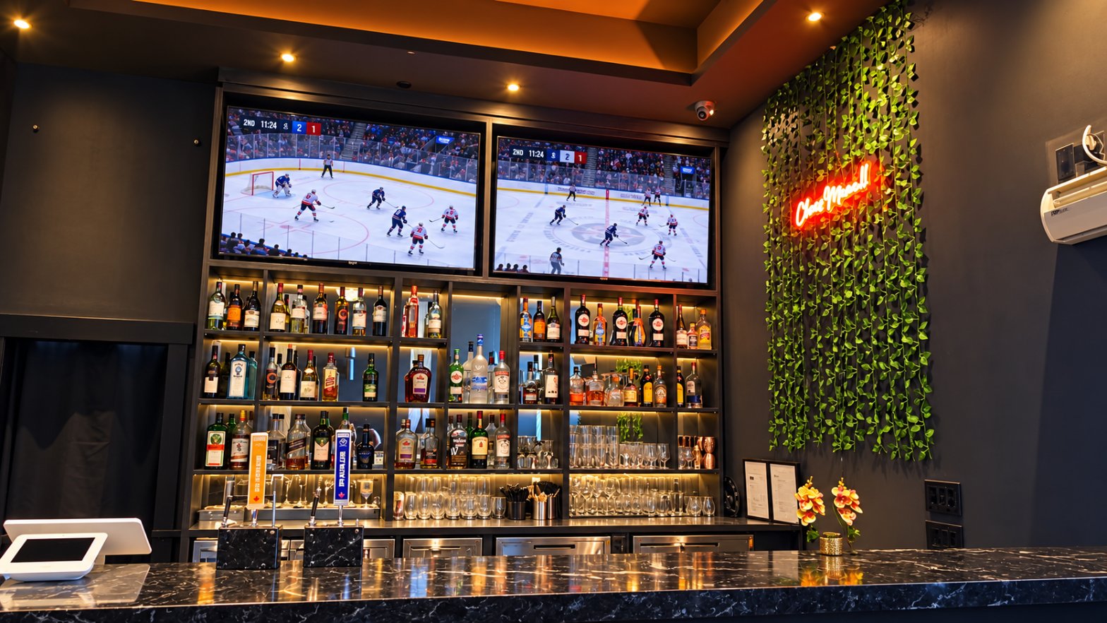 Bar with sports screens, illuminated bottle shelves and greenery