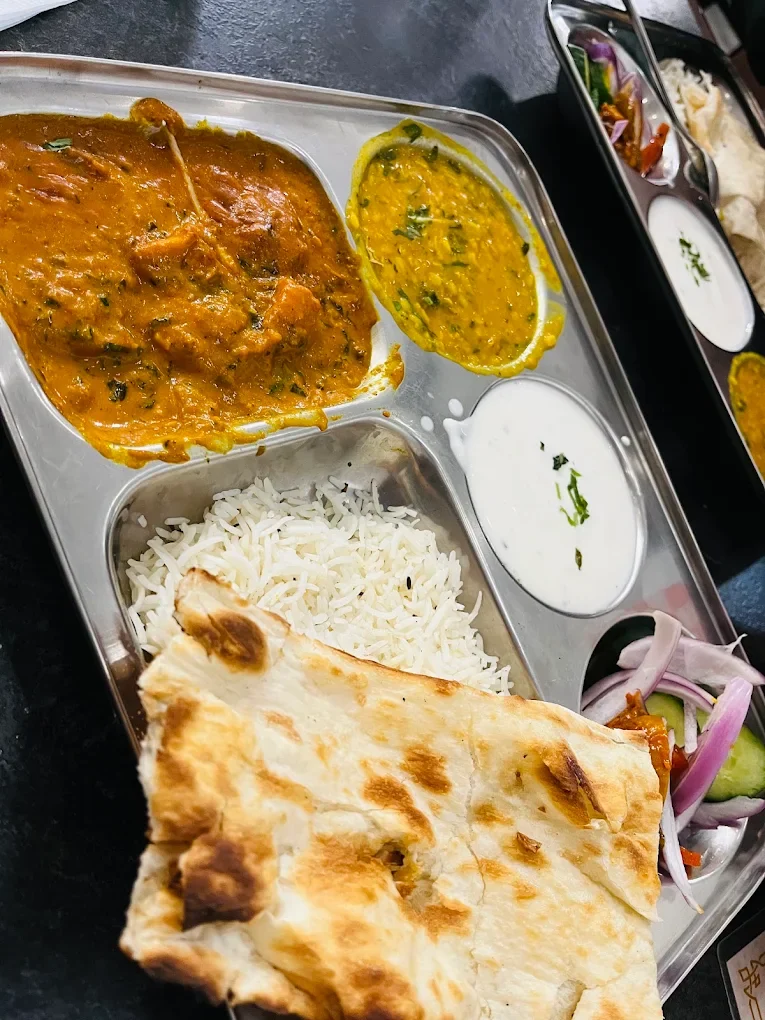 Indian curry thali with rice, naan and raita